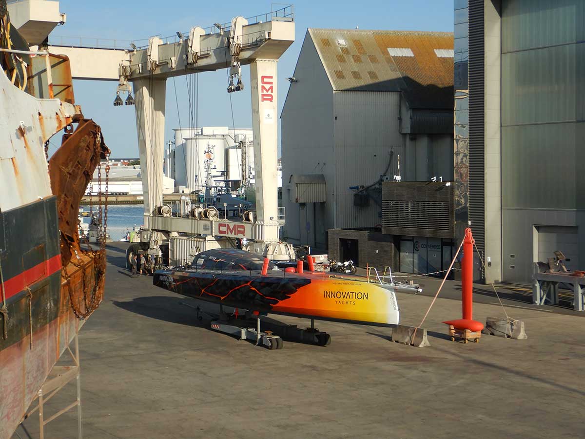IY Open60AAL steht auf einem Trailer neben dem Kiel, vor dem riesigen Travellift