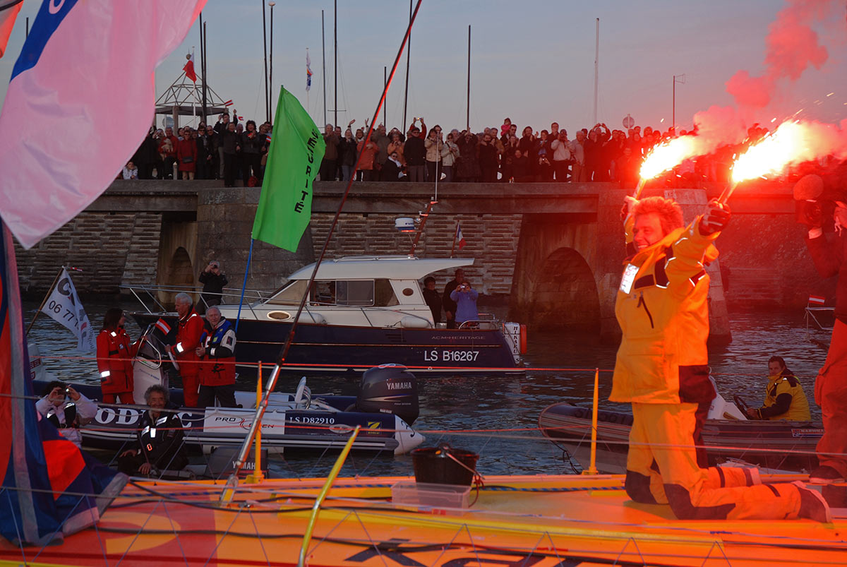 Norbert Sedlacek mit Fackeln in den Händen, kniend and Bord seiner nauticsport kapsch im Kanal von Les Sables d'Olonne nach erfolgreicher Beendigung des Vendée Globe 2008/09