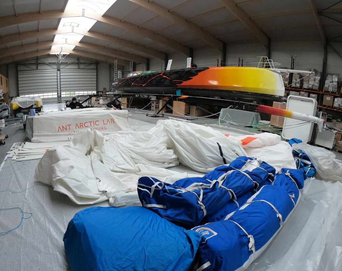 Sails are lying down on the front while two team members are repairing them in the back