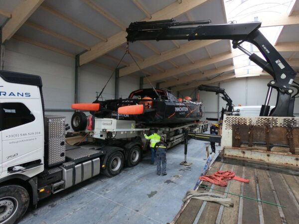 The stern of the Open60AAL is handled by a crane over a truck.