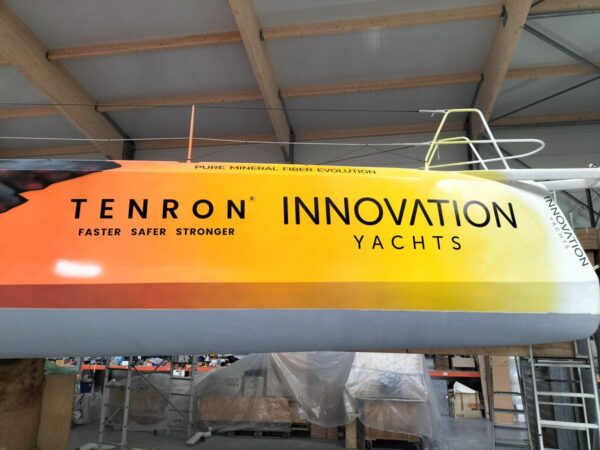 Stickers of Tenron and Innovation Yachts brands on the starboard bow of the Open60AAL.