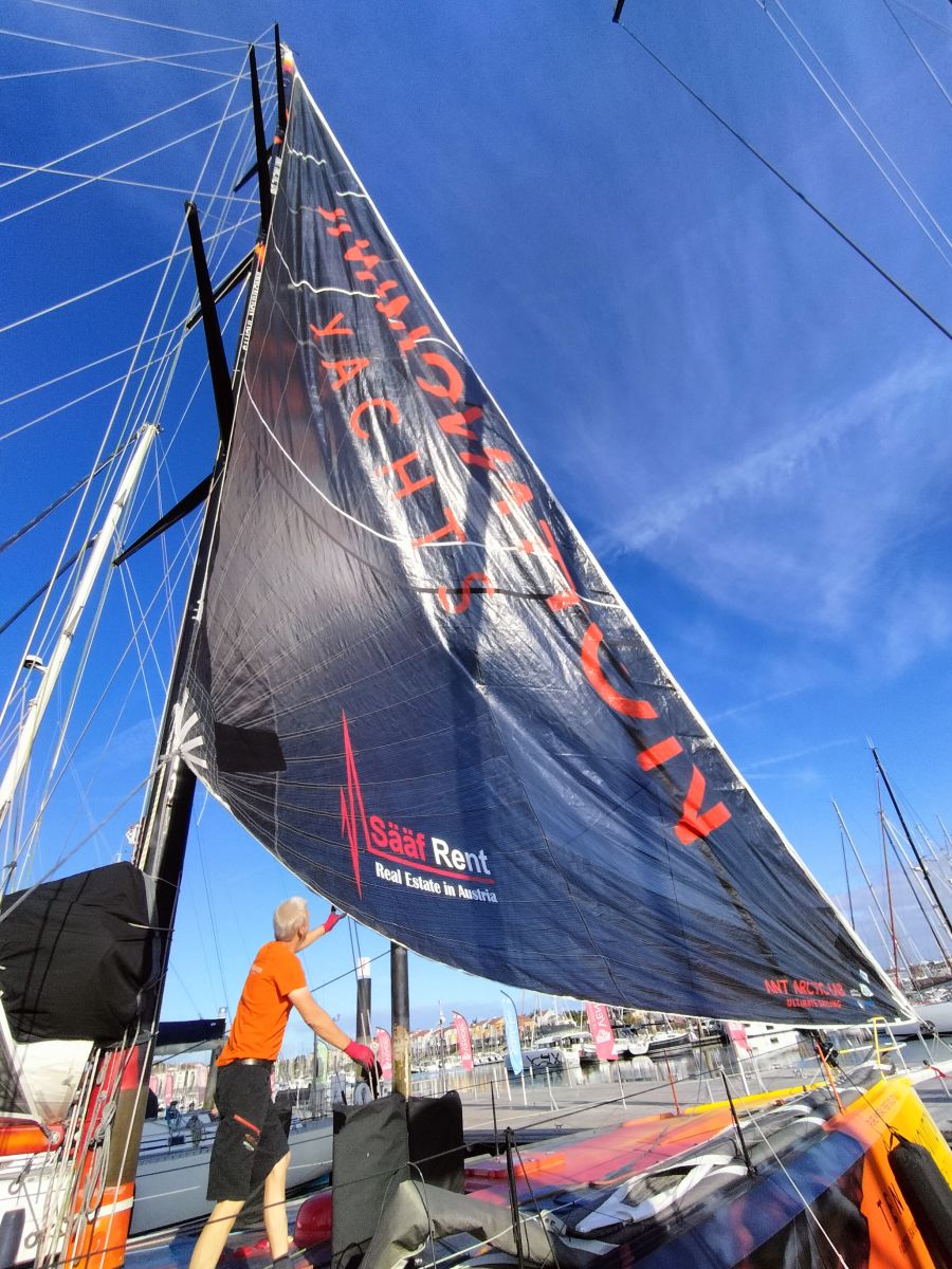 Norbert is standing below a foresail on the Open60AAL - ANT ARCTIC LAB