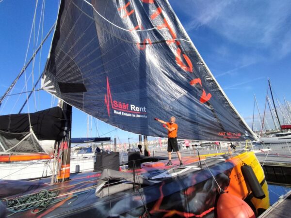 Norbert is standing on the Open60AAL, showing the Sääf Rent branding on a foresail - ANT ARCTIC LAB