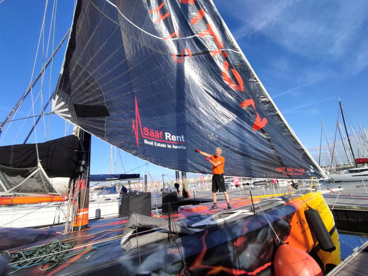 Norbert is standing on the Open60AAL, showing the Sääf Rent branding on a foresail - ANT ARCTIC LAB
