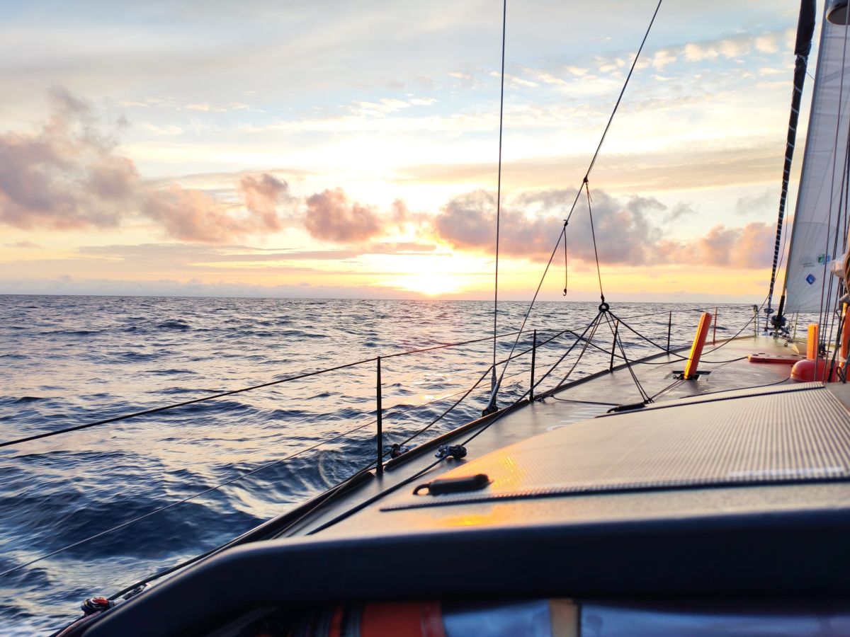 Der Backbordbug der Open60AAL vor einem golden leuchtenden Sonnenuntergang, aufgenommen vom Steuerstand aus. – ANT ARCTIC LAB