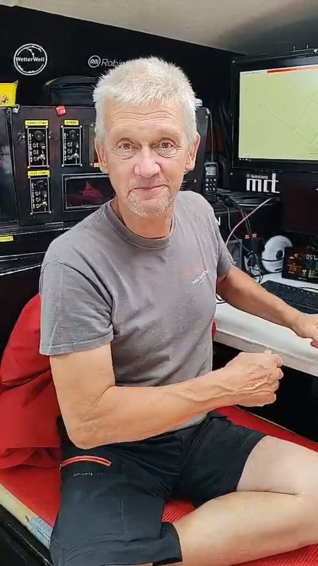 Norbert est assis dans le cockpit de l'Open60AAL, souriant, devant les écrans. - ANT ARCTIC LAB