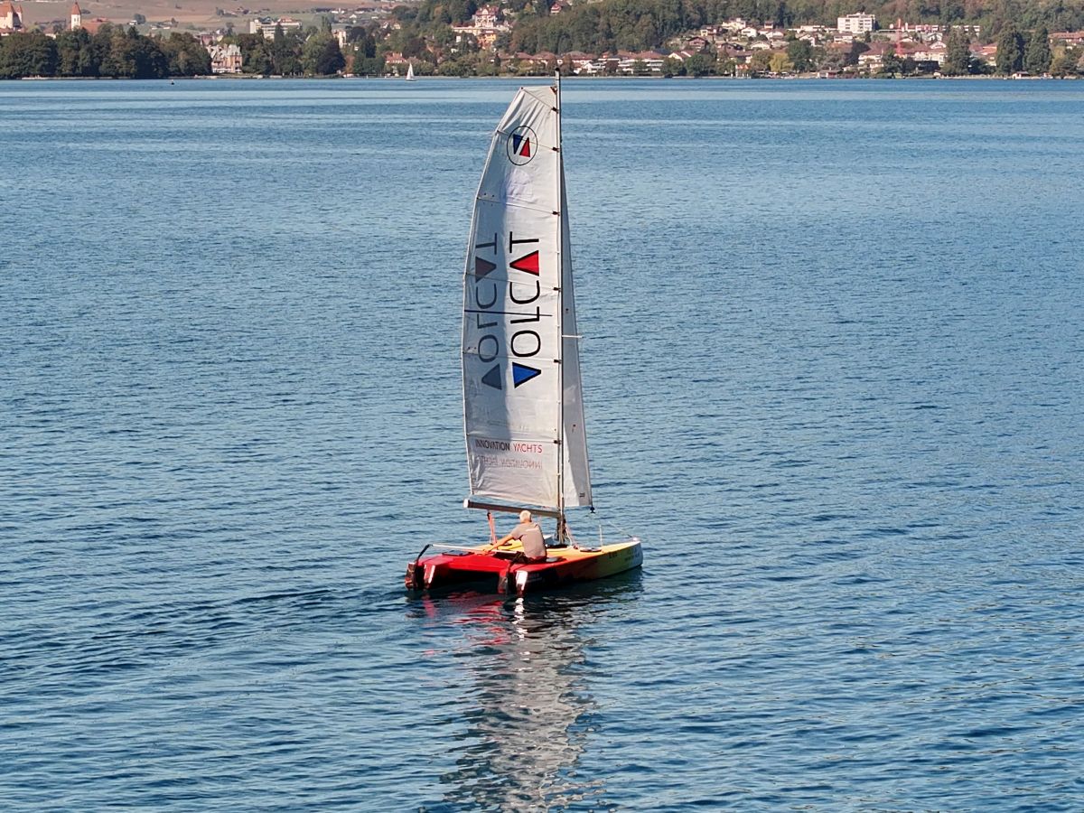 Norbert navigue sur le Volcat16, version « Volcano », sur le lac de Thoune, avec vue sur la petite ville en arrière-plan. - INNOVATION YACHTS