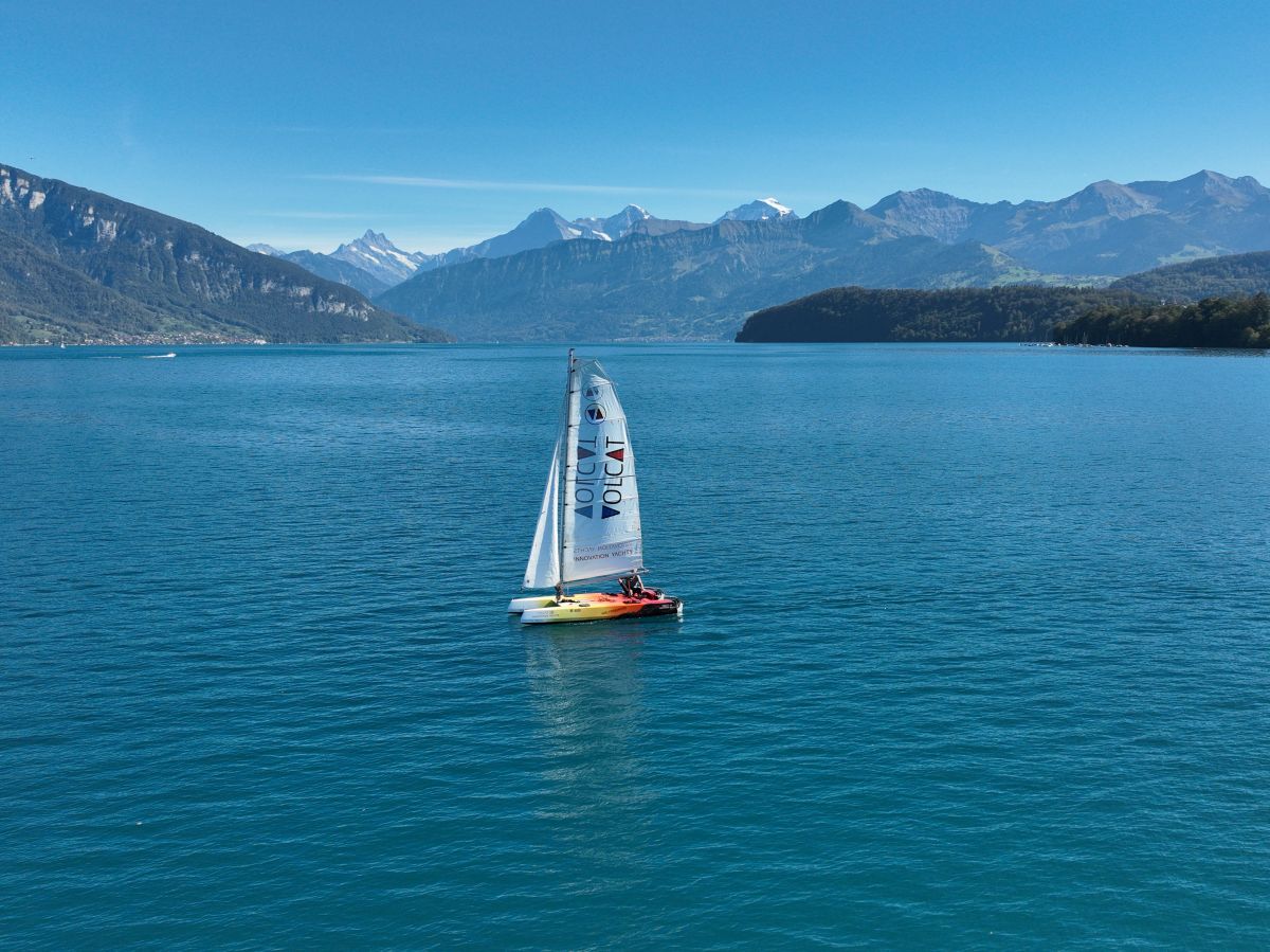 Version « Volcano » du Volcat16 naviguant sur le lac de Thoune, avec ses voiles et son logo bien visibles, offrant une magnifique vue sur les montagnes qui entourent le lac. - INNOVATION YACHTS
