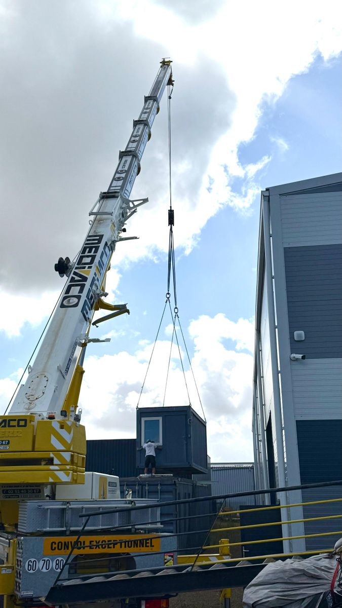 Une grue Mediaco soulève un petit conteneur pour le placer au-dessus d'un plus grand. - INNOVATION YACHTS